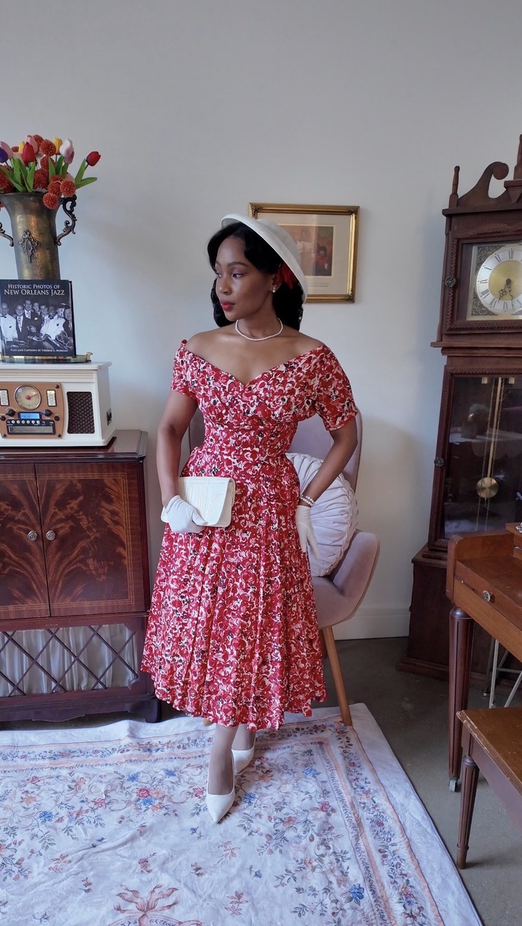 Red floral off-shoulder dress with a white hat and clutch